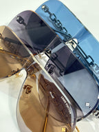 Sunglasses with stacked lenses and chain accents in brown, navy, and clear tones