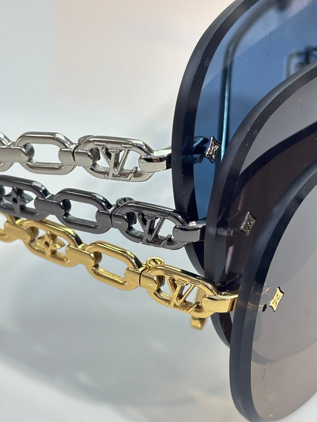 Gold-tone sunglasses chain detail on metal frame with dark lens edge