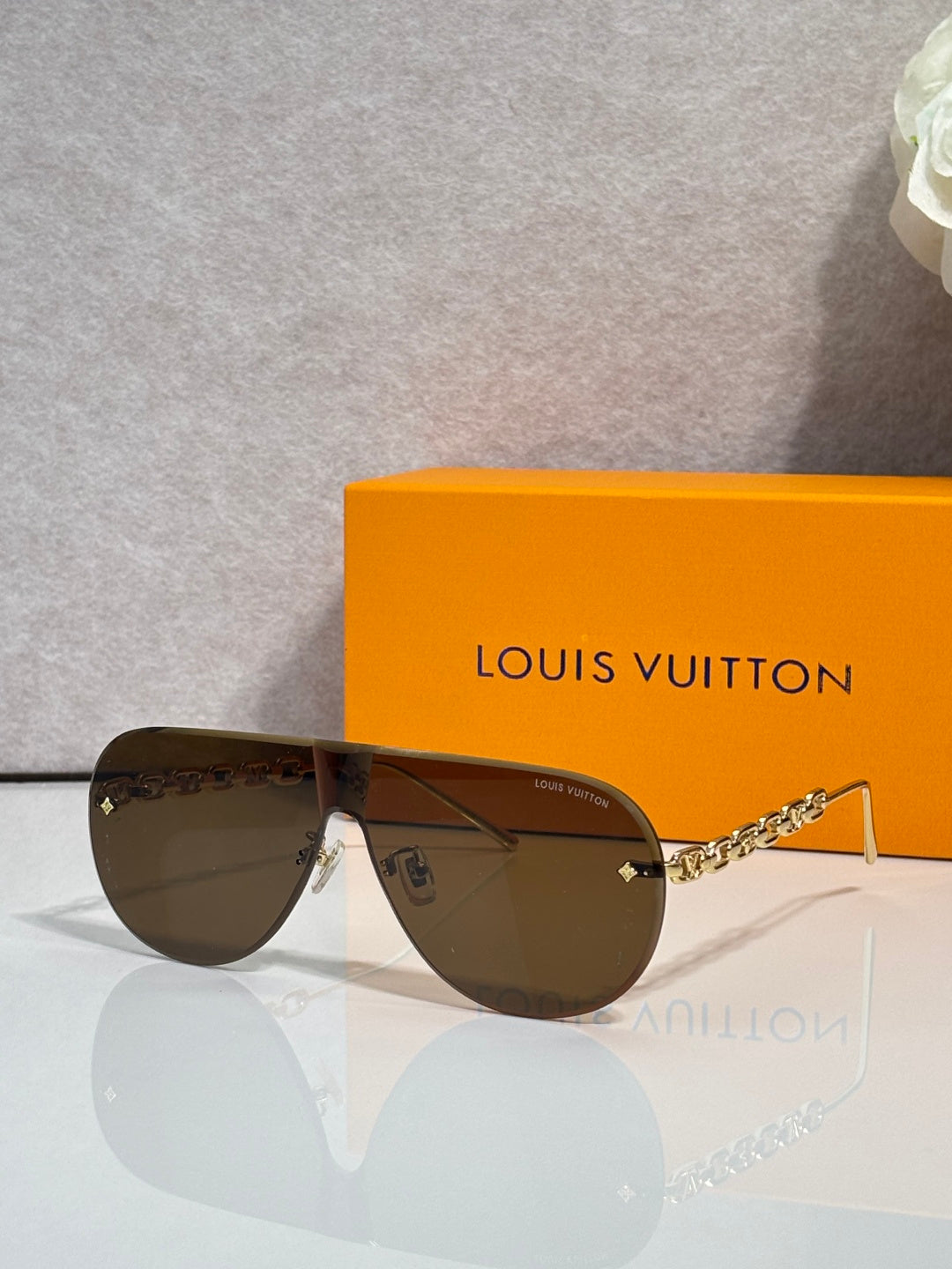 Sunglasses with brown-tinted lenses and gold-tone chain temple, metal wrap arms