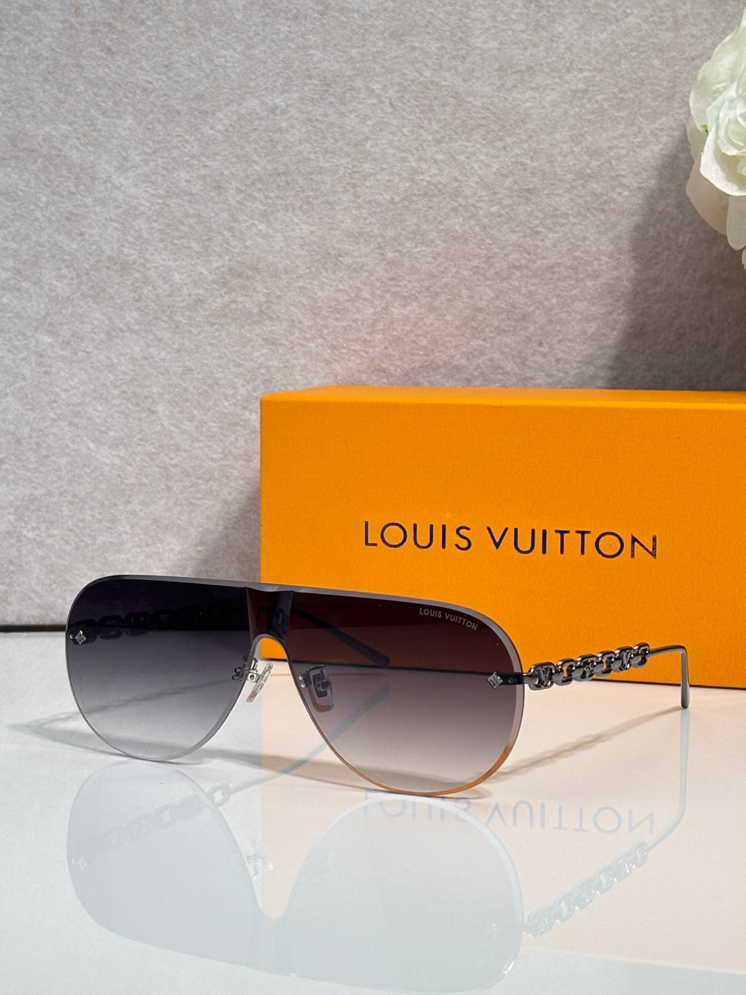 Sunglasses with dark lenses and gold-tone chain detail, aviator-style metal frame