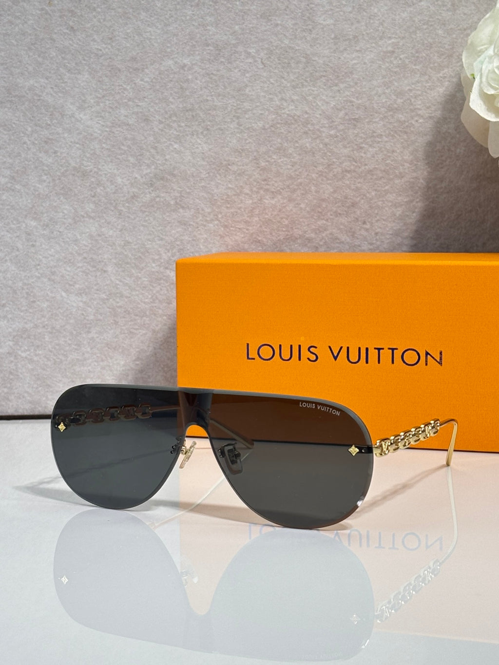 Sunglasses with dark lenses and gold-tone chain temple, aviator-style frame