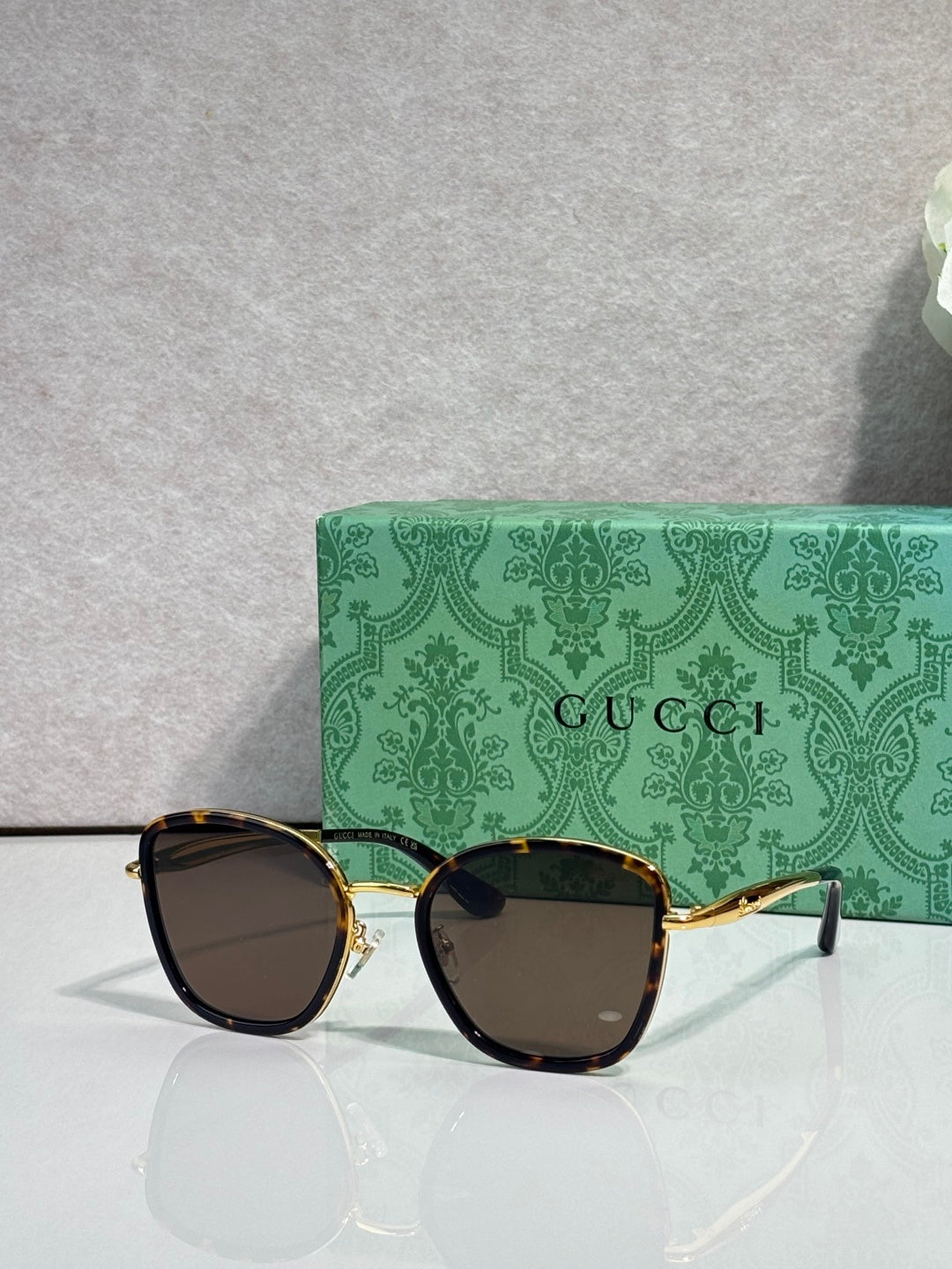 Gucci sunglasses with gold frame, dark tortoiseshell rims, and tinted lenses