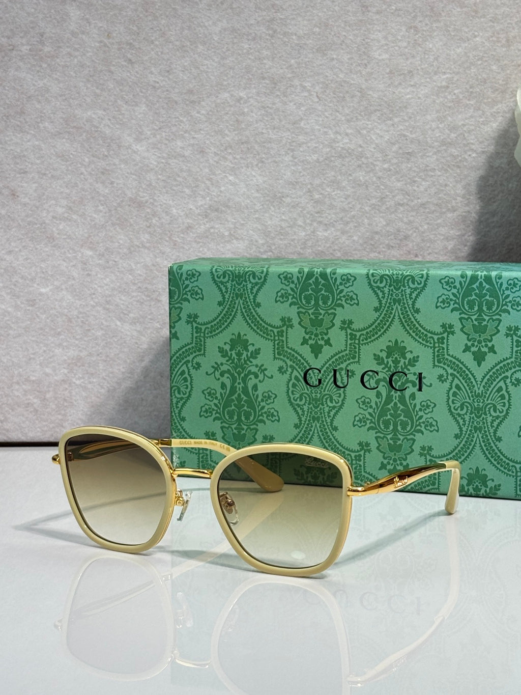 Gucci sunglasses with gold frame, pale lenses, and light acetate square rims