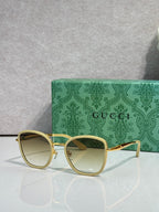 Gucci sunglasses with gold frame, pale lenses, and light acetate square rims