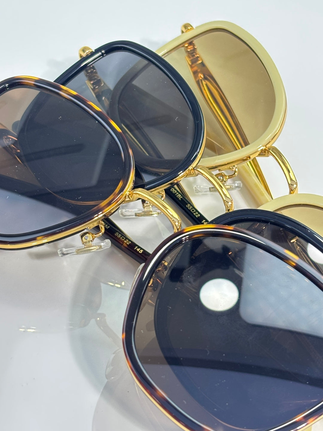 Gucci sunglasses with gold and navy frames, stacked with tinted lenses