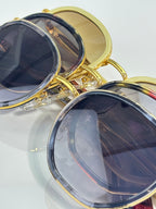 Sunglasses close-up of blue-tinted round lenses with gold-tone frames.