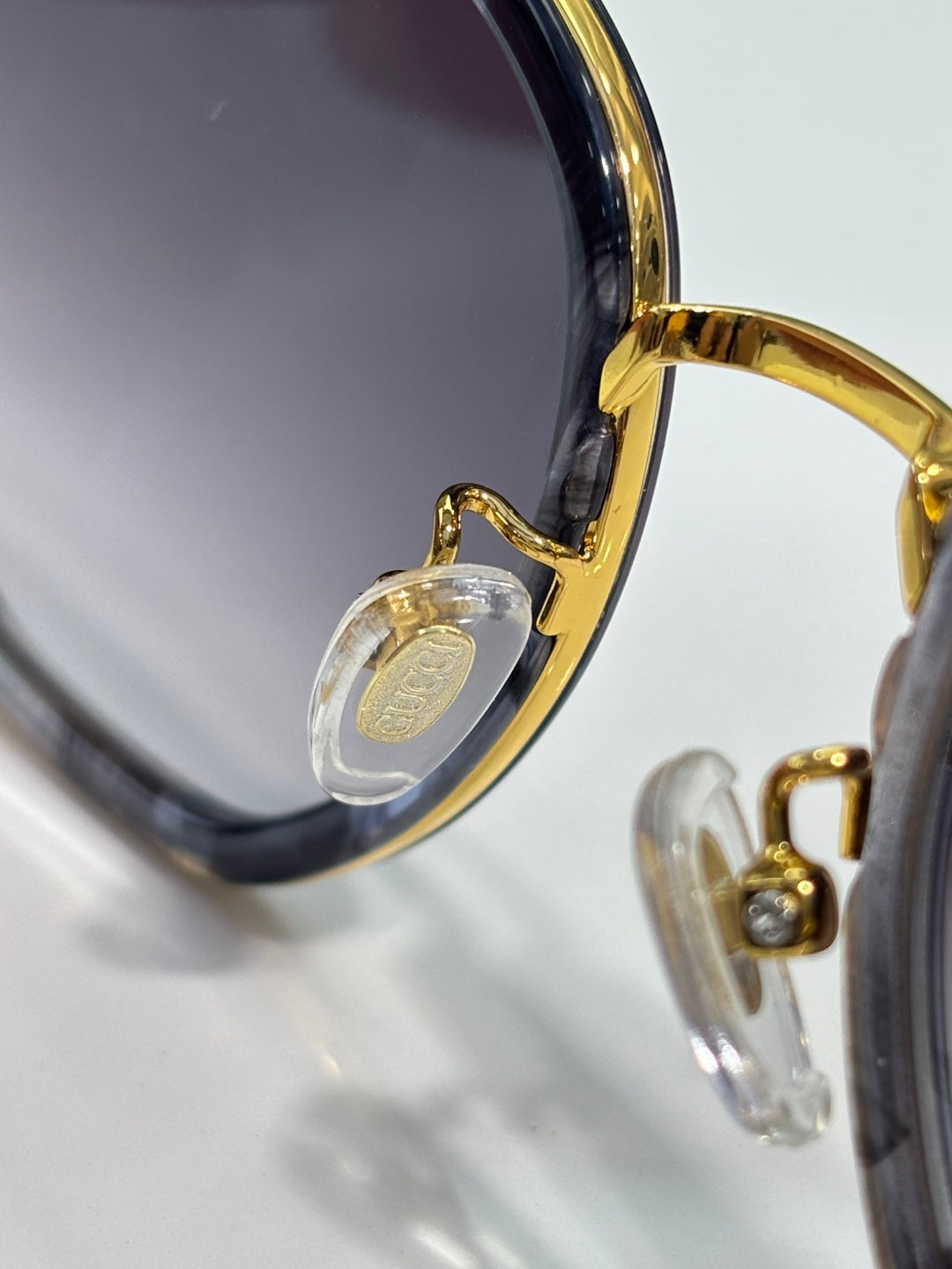 Sunglasses close-up of gold hinge and clear charm on temple.