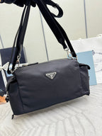 Prada dark nylon handbag with top handles and shoulder strap, angled side view with logo.