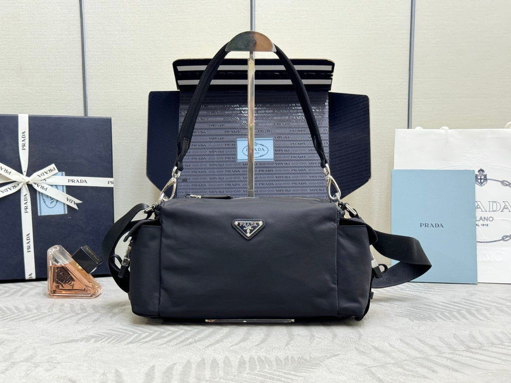 Prada dark nylon handbag with top handles, shoulder strap, and front triangle logo.