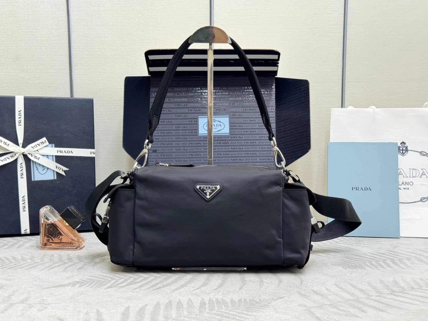 Prada dark nylon handbag with top handles, shoulder strap, and front triangle logo.