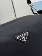 Prada dark nylon handbag front triangle logo patch with metal border.