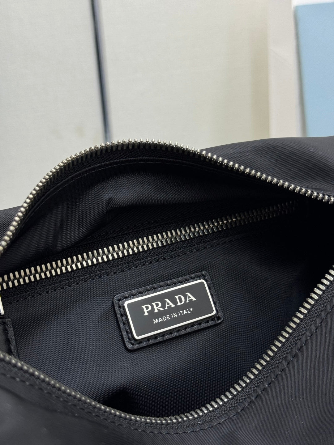 Prada dark nylon bag interior label reading PRADA with zip pocket detail.