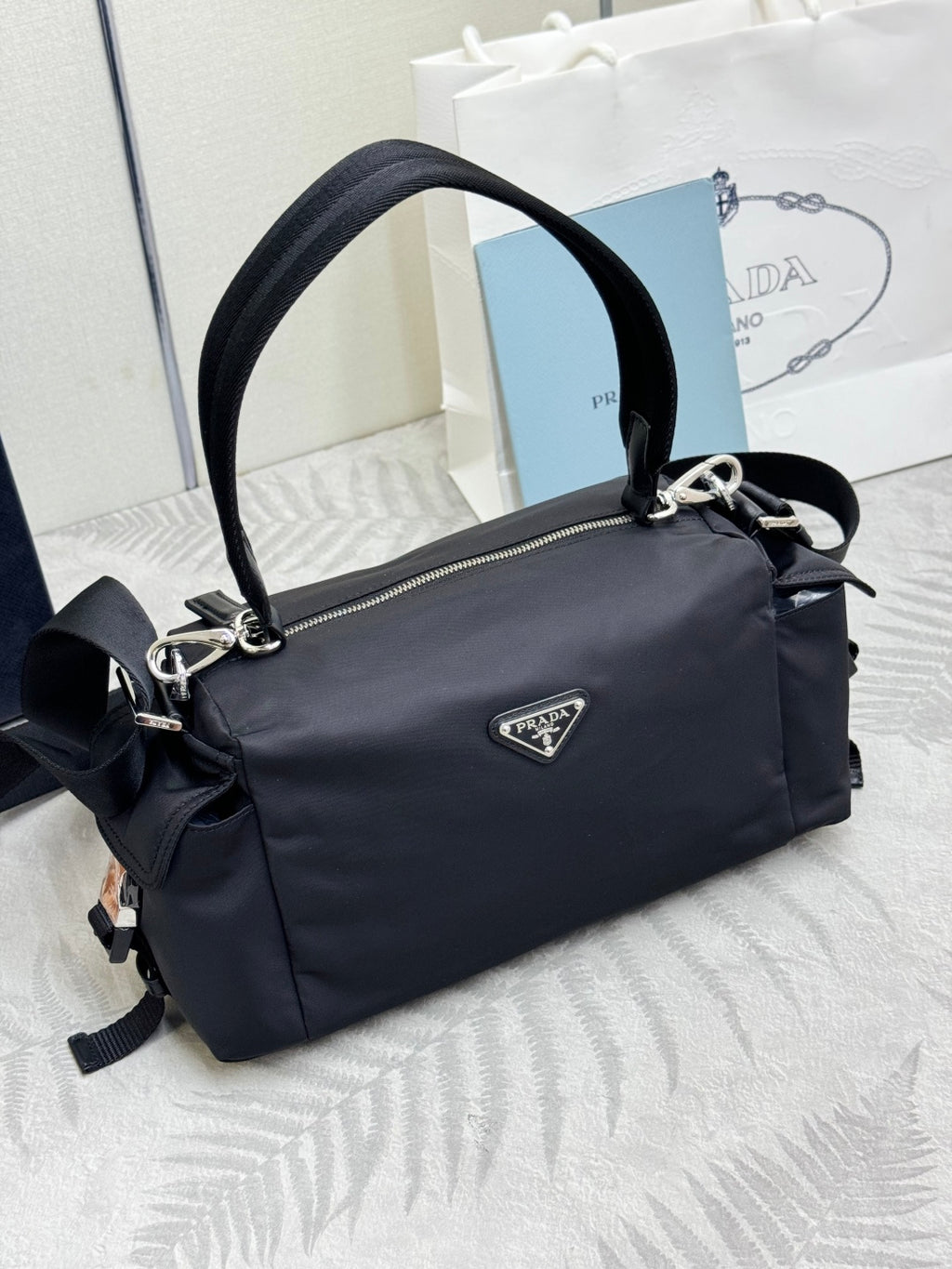 Prada dark nylon handbag with curved top handle and shoulder strap, front logo patch.