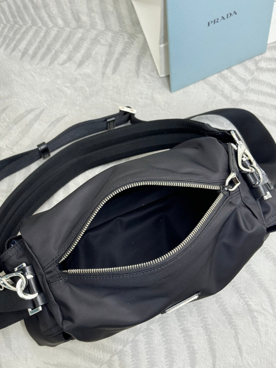 Prada dark nylon mini bag with zip front pocket and shoulder strap, angled top view.