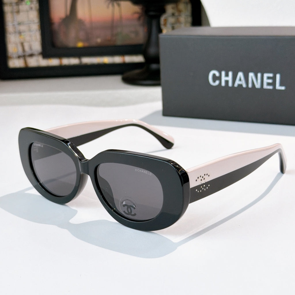 Sunglasses with black frames and dark lenses, rounded cat-eye shape with Chanel logo