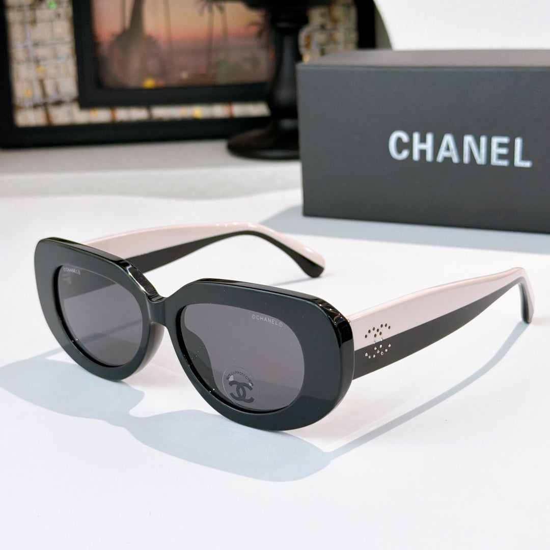 Sunglasses with black frames and dark lenses, rounded cat-eye shape with Chanel logo