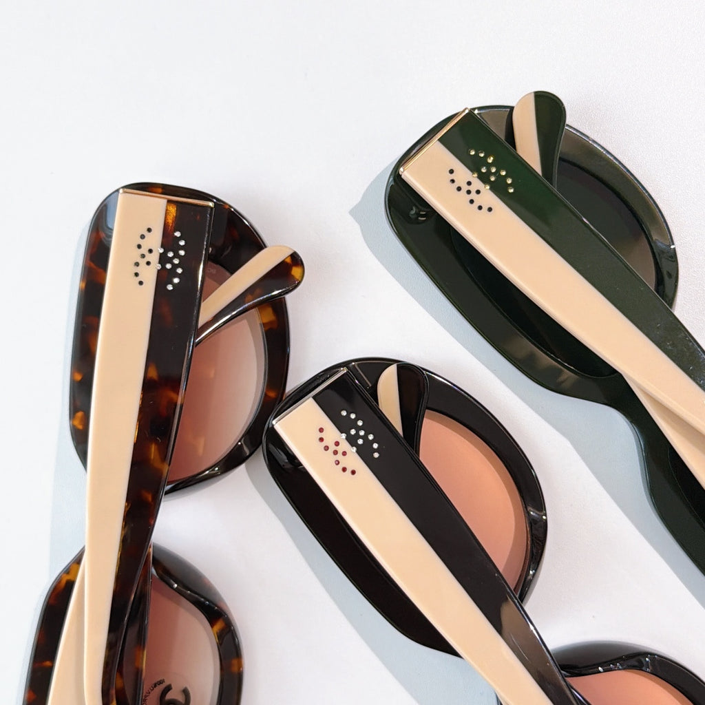 Sunglasses close-up showing tortoiseshell, black, and green frames with perforated temple detail