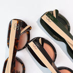 Sunglasses close-up showing tortoiseshell, black, and green frames with perforated temple detail