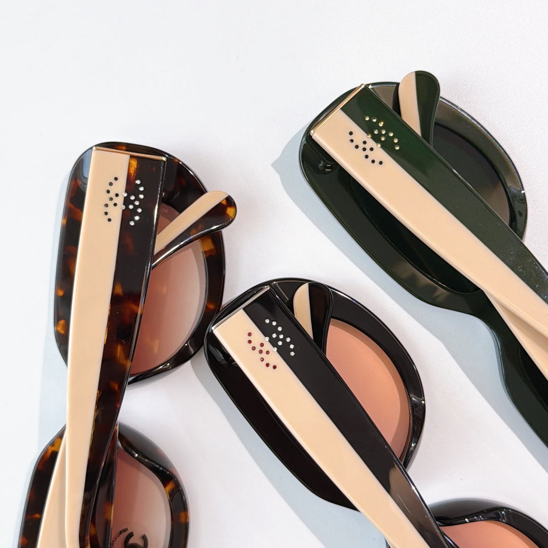 Sunglasses close-up showing tortoiseshell, black, and green frames with perforated temple detail