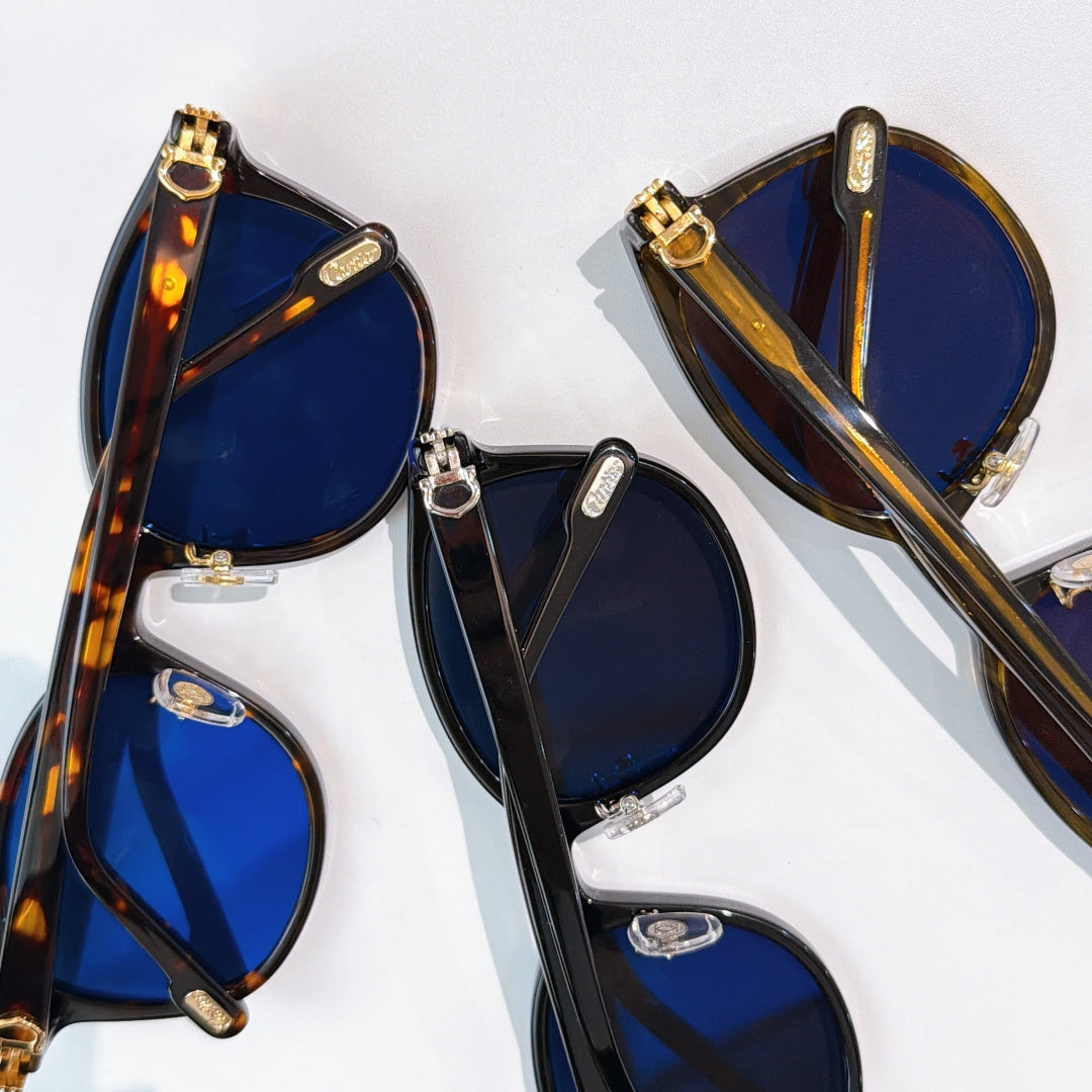Cartier sunglasses close-up with blue lenses and mixed black/tortoiseshell frames