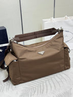 Brown nylon shoulder bag with top zipper, adjustable strap, and logo triangle tag
