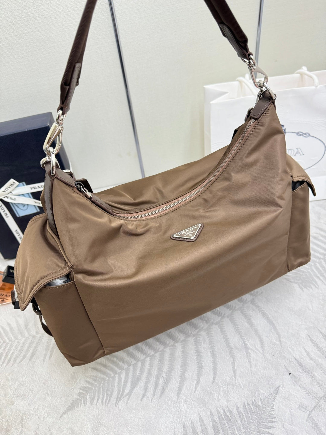 Taupe nylon crossbody hobo bag with side strap, top zipper, and metal clasp