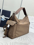 Tan nylon hobo bag with shoulder strap, front pocket flap, and metal hardware