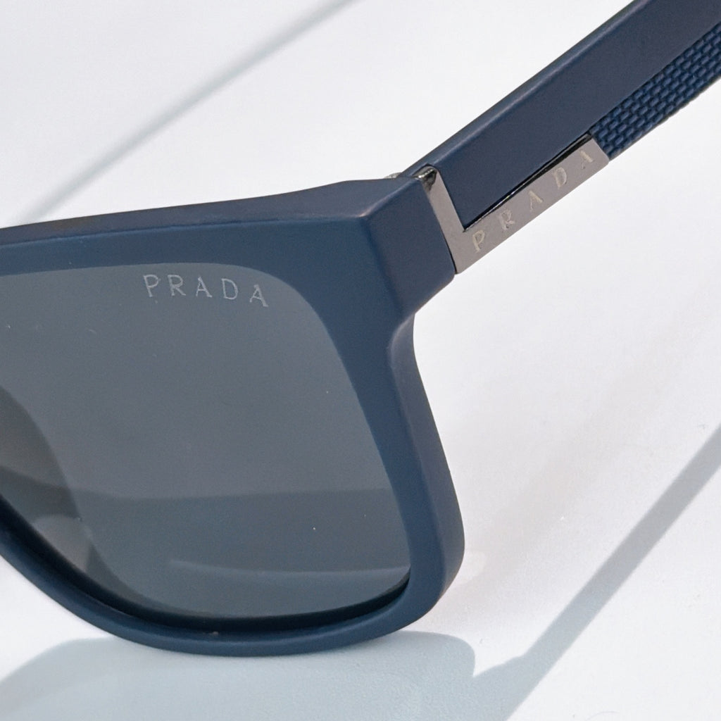 Sunglasses close-up: navy frame with textured temple and dark lens