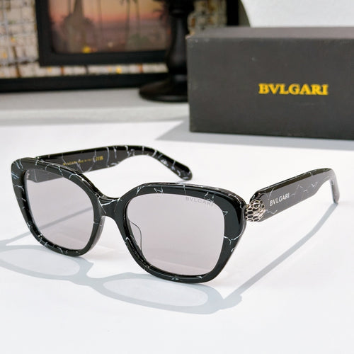 Black cat-eye eyeglasses with dark lenses and gold logo detail