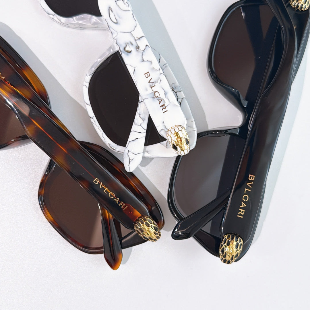 Assorted eyeglasses with white marbled, brown, and black frames; gold logo details