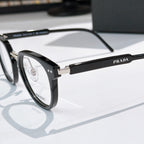 Prada glasses, close-up black frame with silver temples and gold logo bar