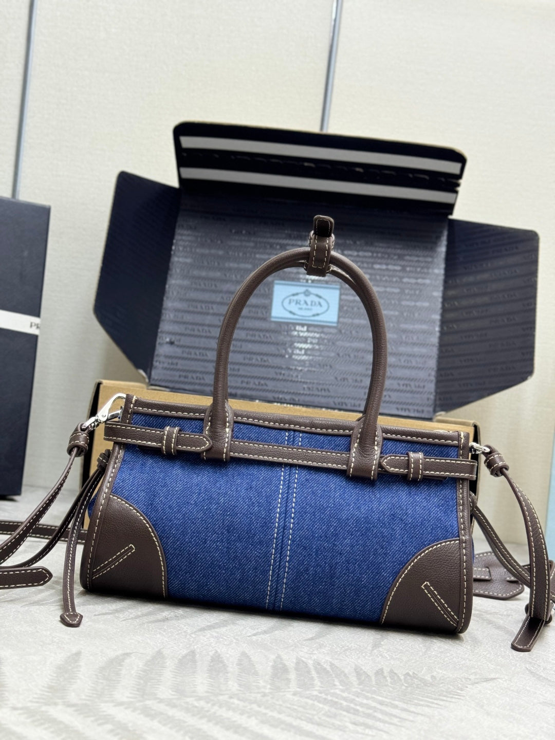 Blue denim Prada handbag with top handle, crossbody strap, and logo hardware