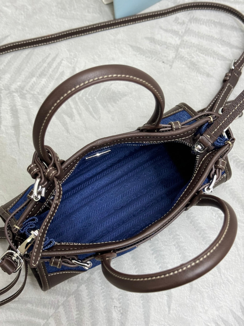 Blue denim Prada handbag with brown leather crossbody strap and silver hardware
