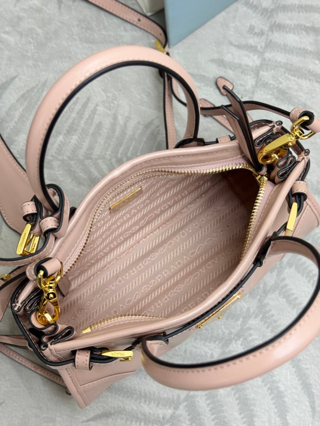 Prada light pink mini bag with zip-top opening, gold hardware, crossbody strap