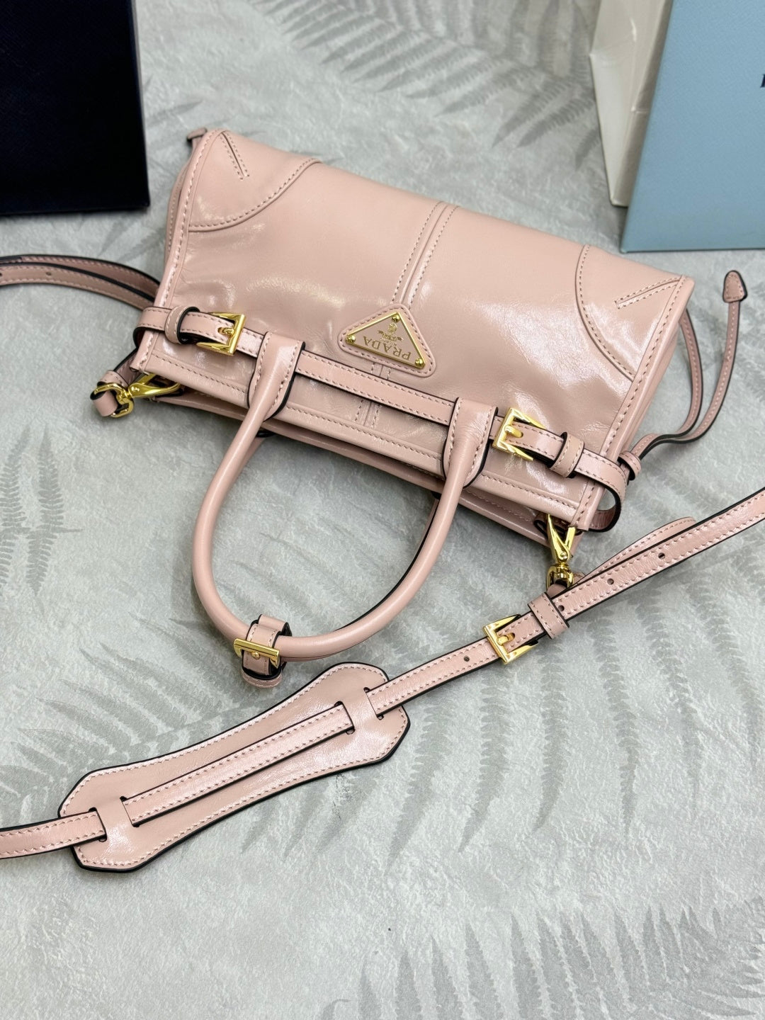 Prada light pink mini bag with front belt strap, crossbody strap, gold hardware