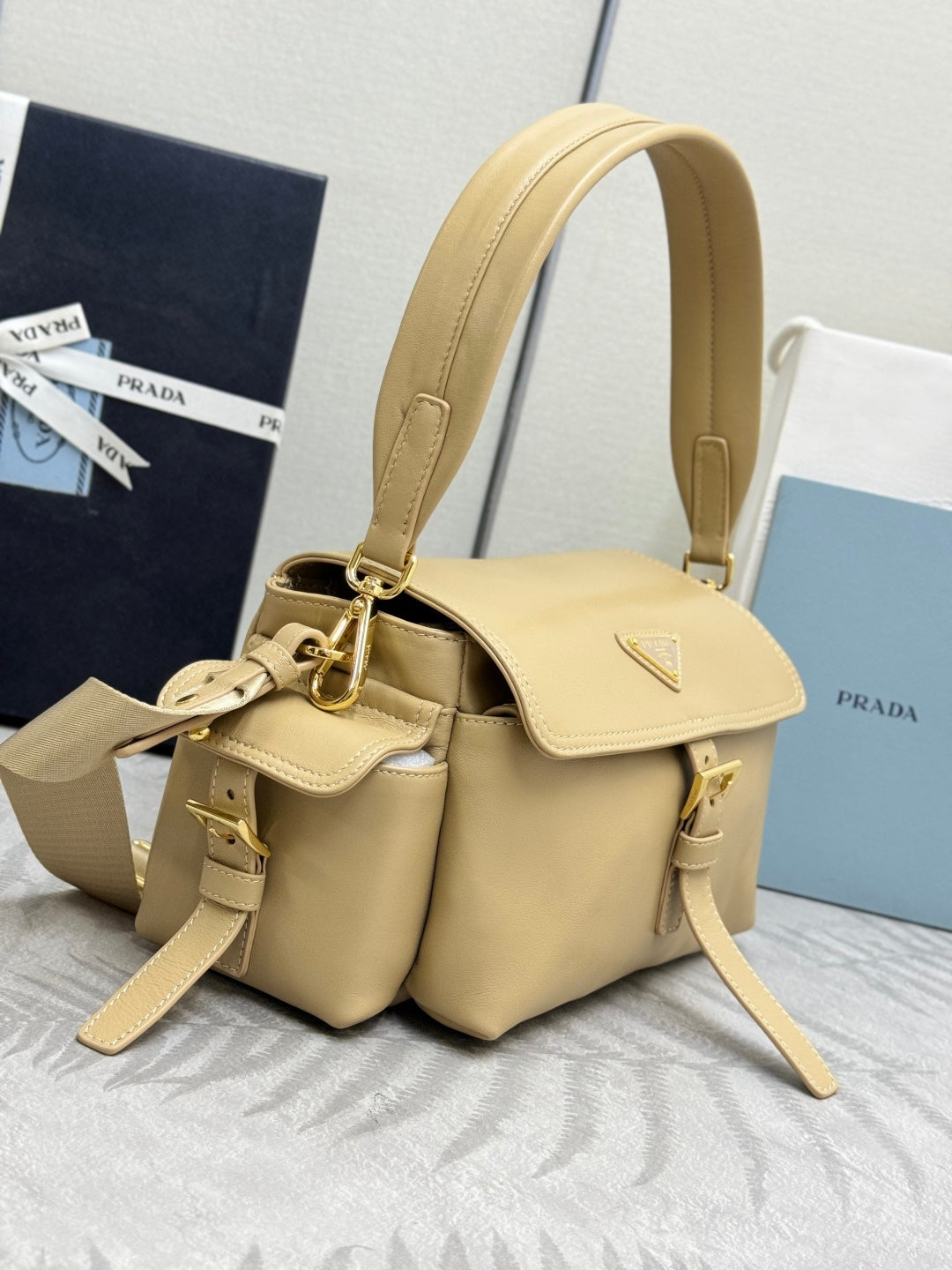Beige leather tote-style bag with dual handles, flap front, and gold hardware