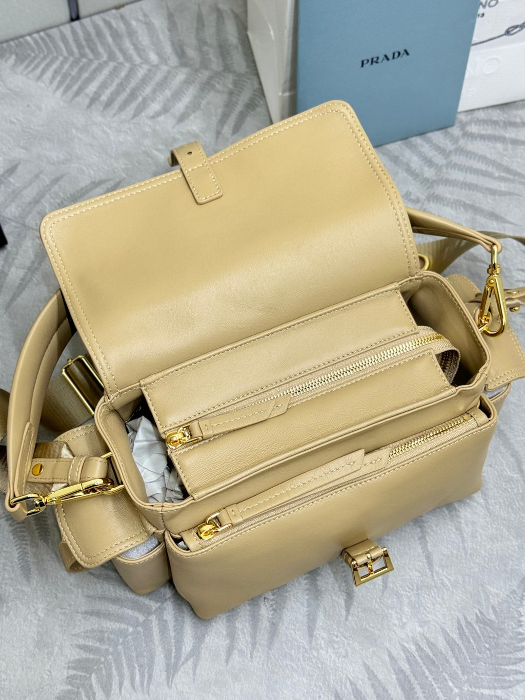 Beige leather bag interior view with zip pocket, tabs, and structured front flap