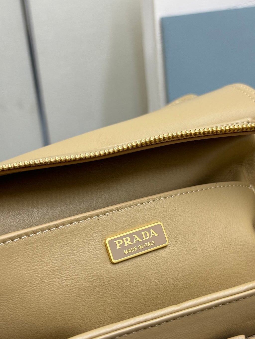 Beige leather bag with gold zipper edge and PRADA logo label on front panel