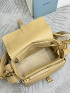 Beige leather mini backpack-style bag with flap, straps, and gold zipper hardware