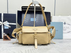 Beige leather shoulder bag with top handle, flap front, gold hardware, and logo plaque