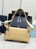 Beige leather handbag with shoulder strap, flap top, front logo plate, and gold trim