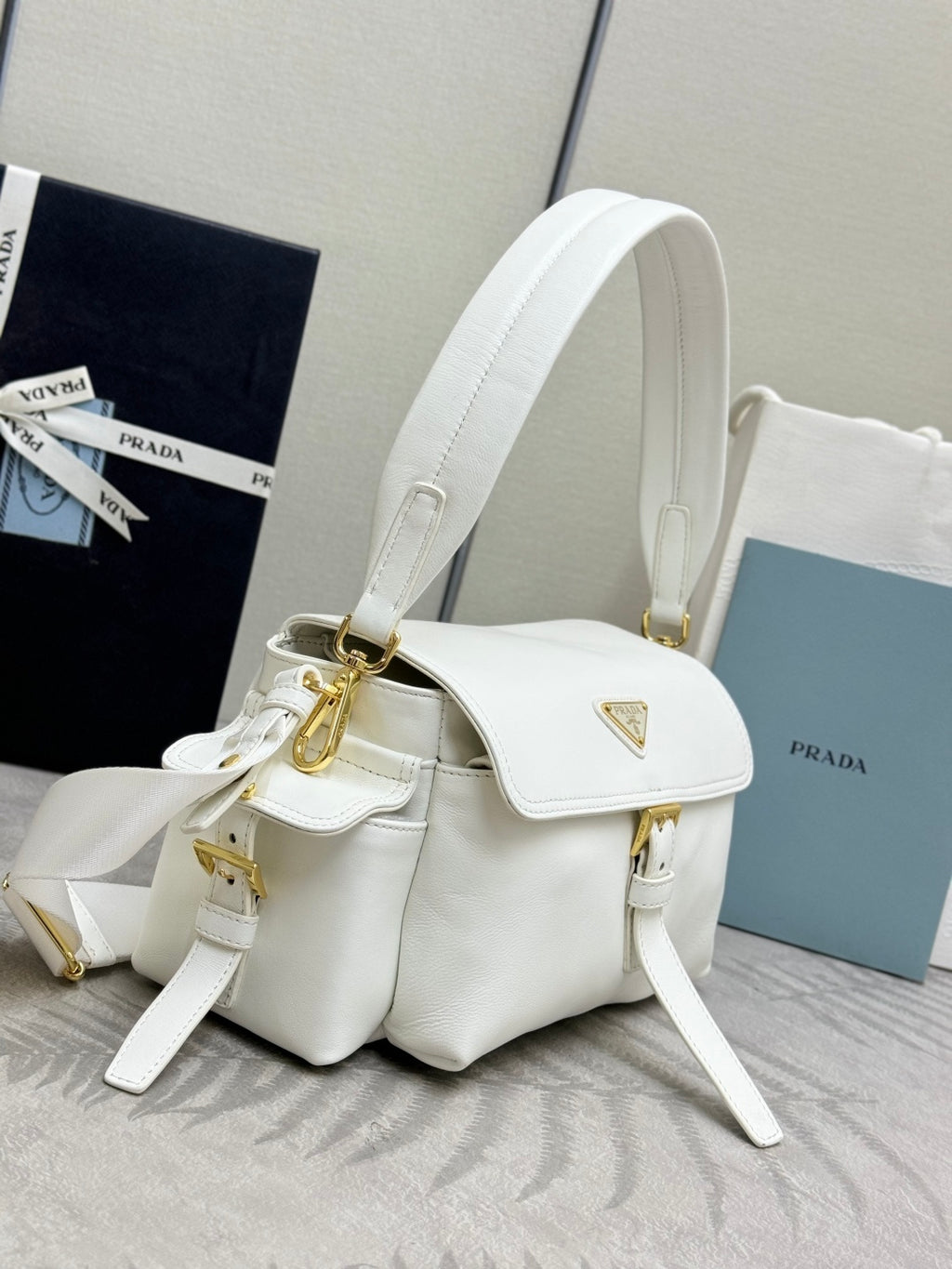White Prada mini handbag with front flap, gold hardware, and side straps
