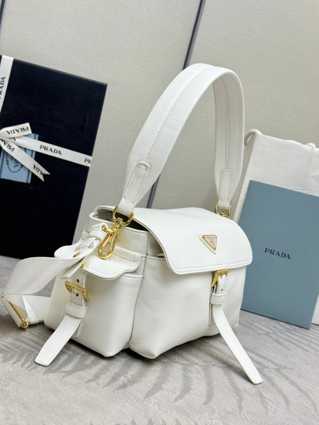 White Prada mini handbag with front flap, gold hardware, and side straps