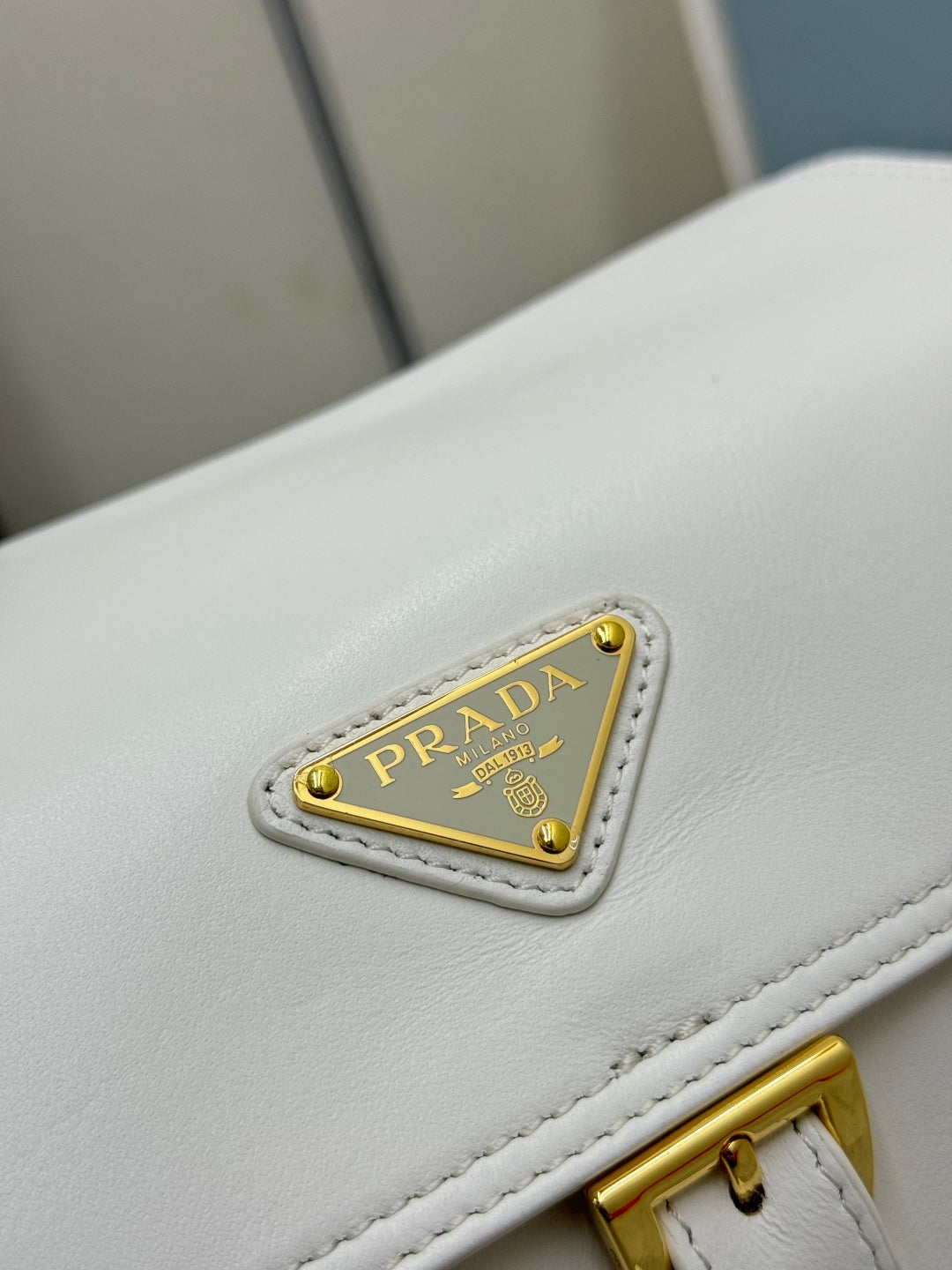 White Prada handbag logo patch with gold lettering on leather flap