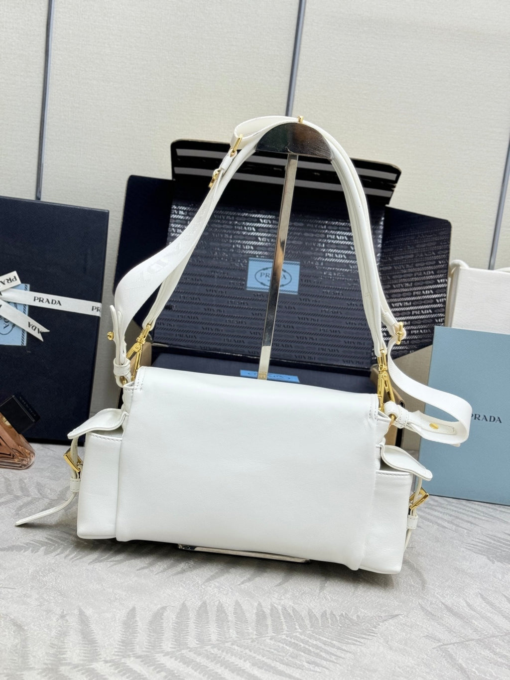 White Prada handbag worn crossbody, with gold-tone hardware and front flap