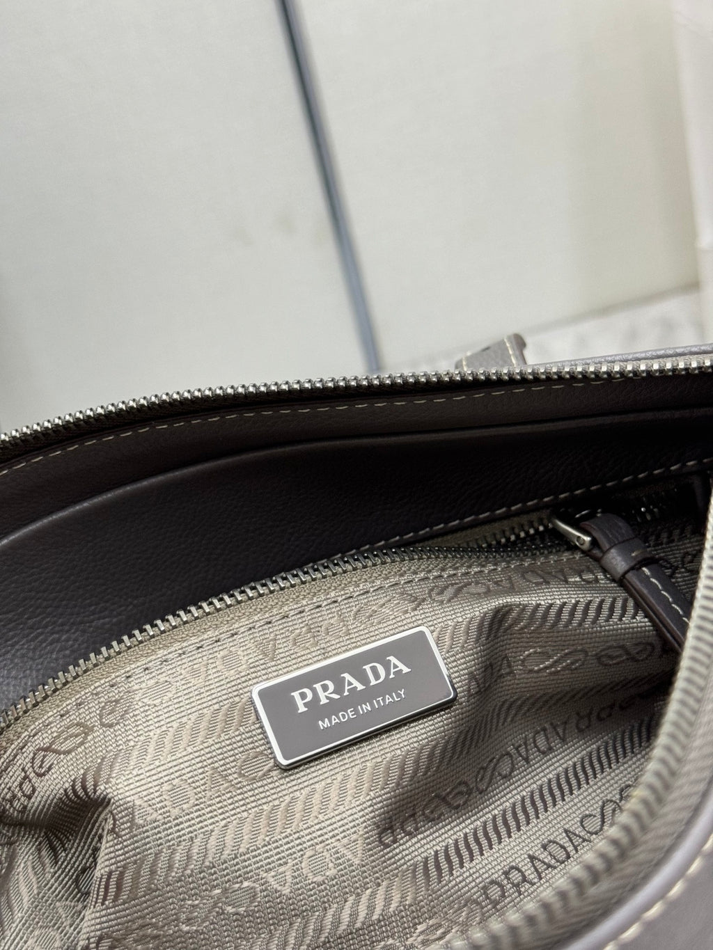 Prada logo label on jacquard lining inside a zipped compartment.