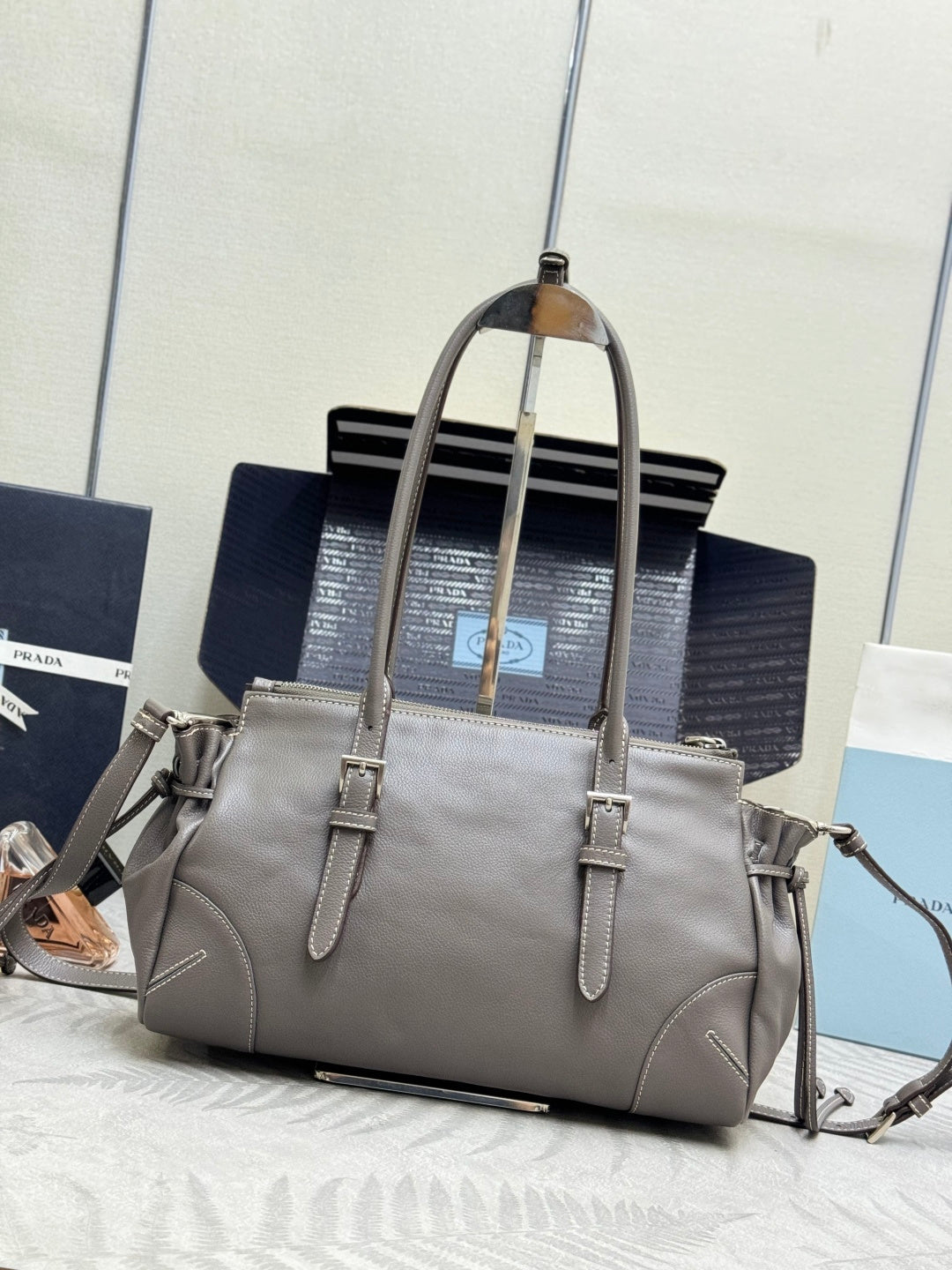 Prada gray leather tote with shoulder strap, front logo, and side details.
