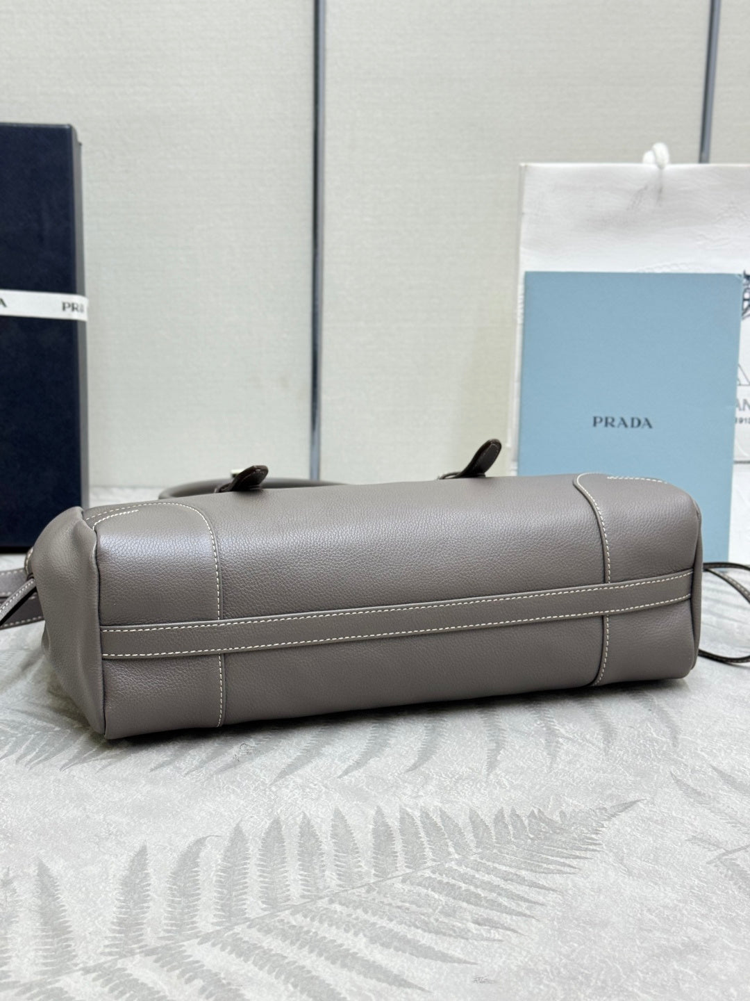 Prada gray leather handbag with horizontal seam and side handle loops.