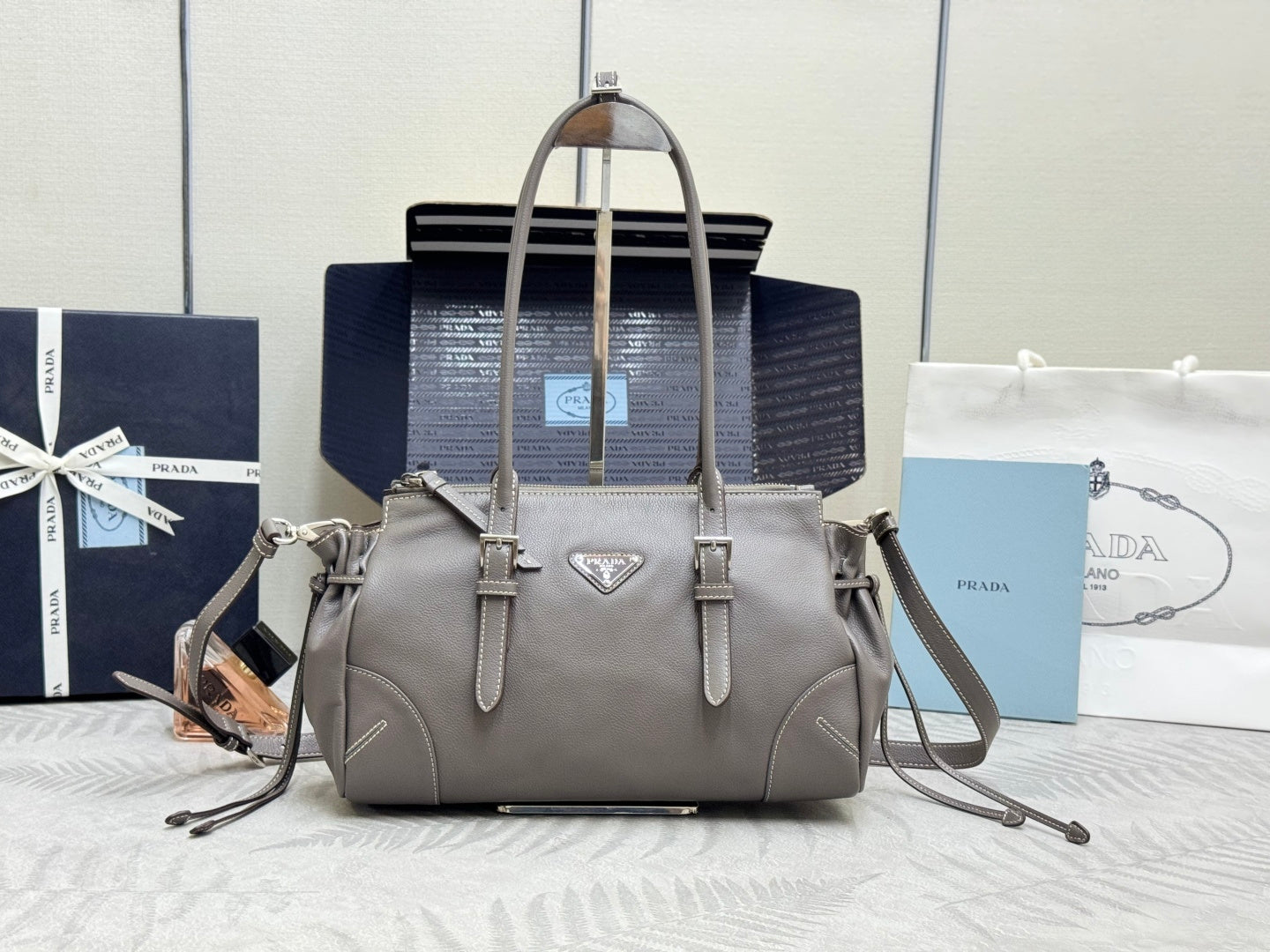 Prada gray leather tote with double handles and triangle logo plaque.