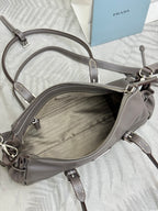 Prada gray leather handbag open with inner zip pocket and metal zipper pull.